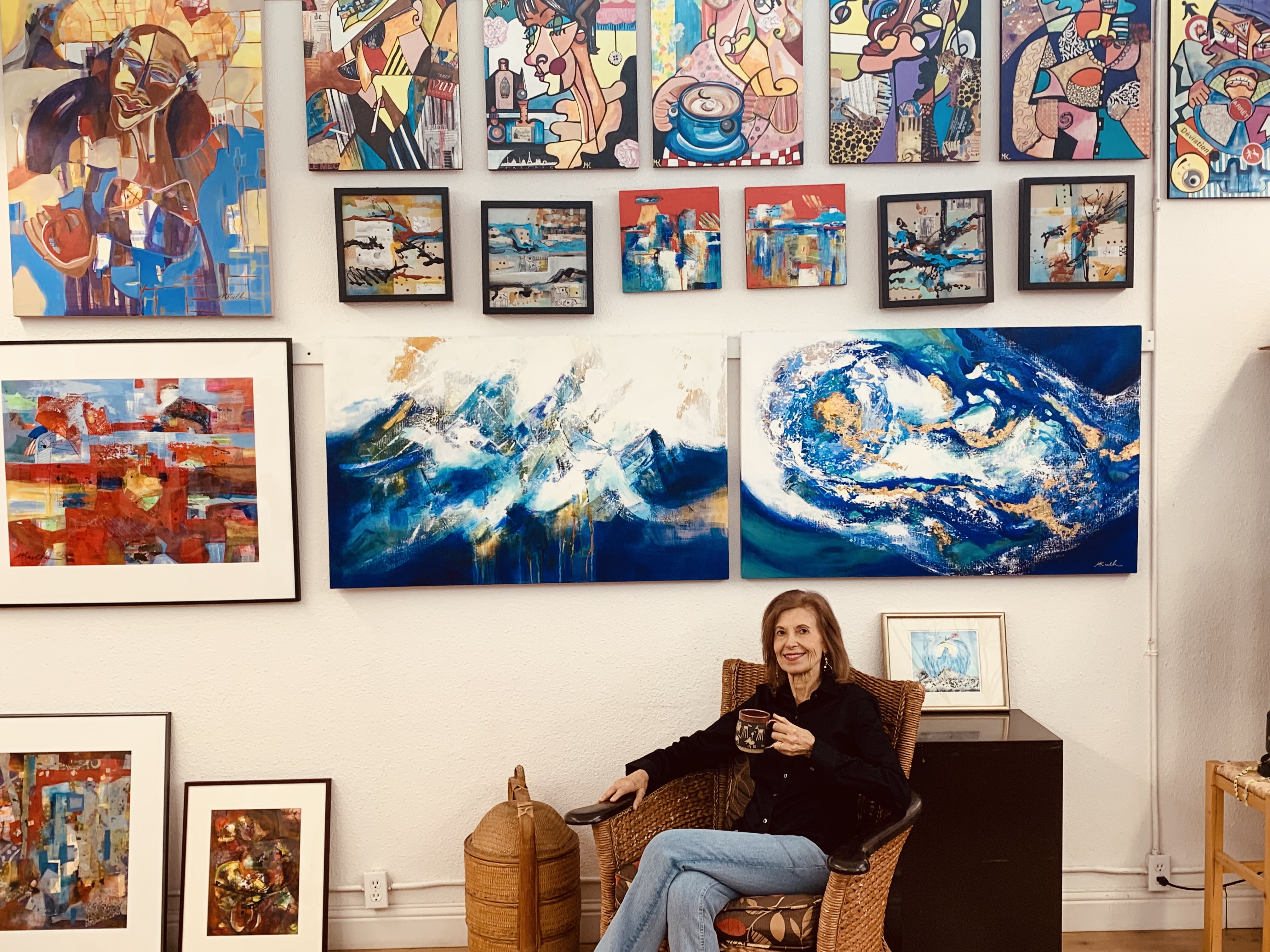 Mary Karlton surrounded by a collection of her paintings and mixed media artwork